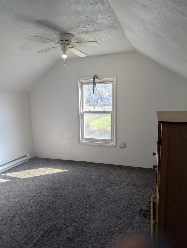 bonus room featuring lofted ceiling, dark colored carpet, ceiling fan, a textured ceiling, and baseboard heating