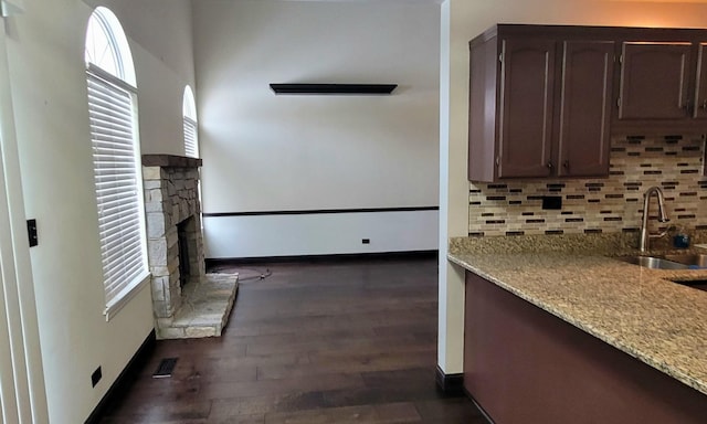 kitchen featuring backsplash, sink, dark hardwood / wood-style floors, light stone countertops, and dark brown cabinets