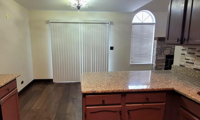 kitchen with decorative backsplash, dark hardwood / wood-style floors, a stone fireplace, and light stone countertops