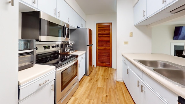 kitchen with white cabinets, light wood-type flooring, sink, and appliances with stainless steel finishes