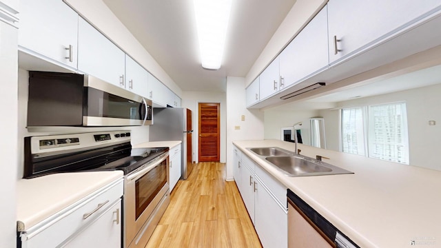 kitchen with white cabinetry, sink, light hardwood / wood-style floors, and appliances with stainless steel finishes