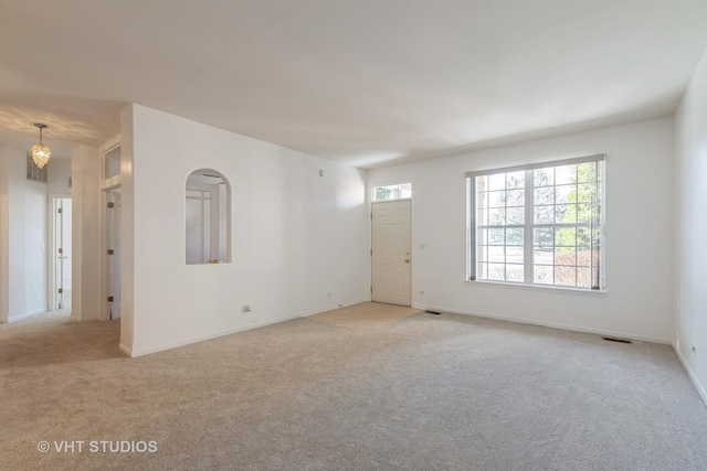 unfurnished room with a notable chandelier and light colored carpet