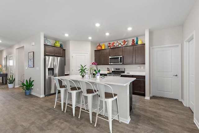 kitchen with a center island with sink, a kitchen bar, sink, stainless steel appliances, and dark brown cabinets