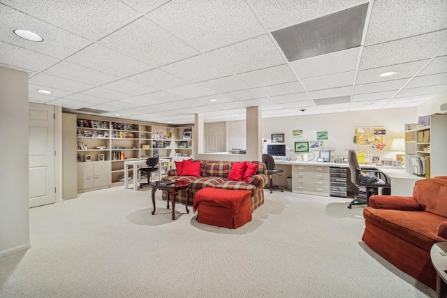 carpeted living room featuring a paneled ceiling, built in desk, and built in shelves