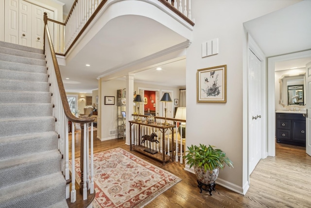 entrance foyer featuring decorative columns, hardwood / wood-style floors, and crown molding