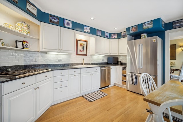 kitchen with light wood-type flooring, stainless steel appliances, white cabinetry, and sink