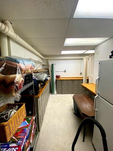 basement featuring a drop ceiling and white fridge