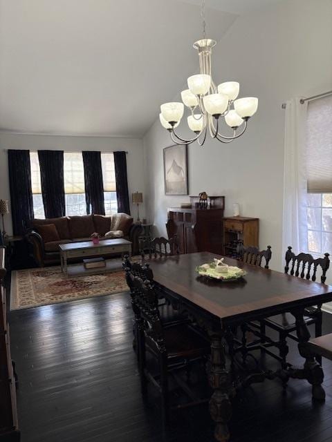 dining room with a notable chandelier, dark wood-type flooring, and vaulted ceiling