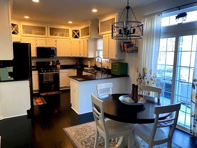 kitchen with sink, an inviting chandelier, range with gas stovetop, decorative light fixtures, and white cabinets