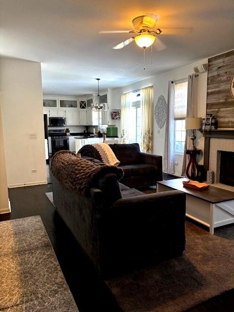 living room with wood walls, a fireplace, and ceiling fan with notable chandelier