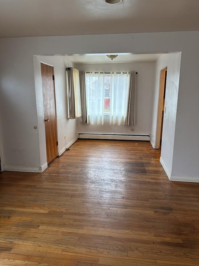 empty room featuring baseboard heating and dark hardwood / wood-style flooring