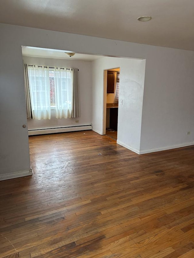 spare room with dark hardwood / wood-style floors and baseboard heating