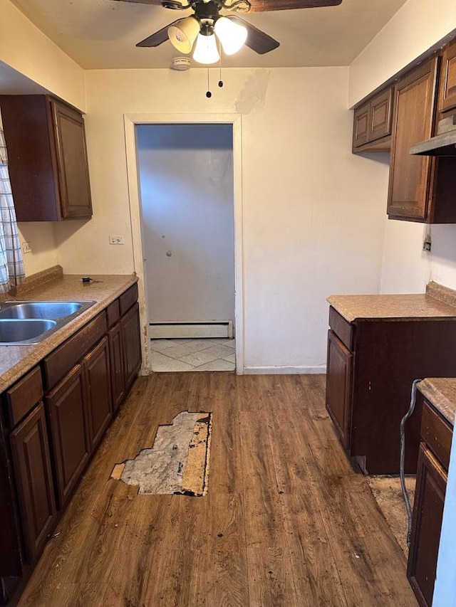 kitchen with dark brown cabinetry, sink, dark hardwood / wood-style floors, ceiling fan, and a baseboard heating unit