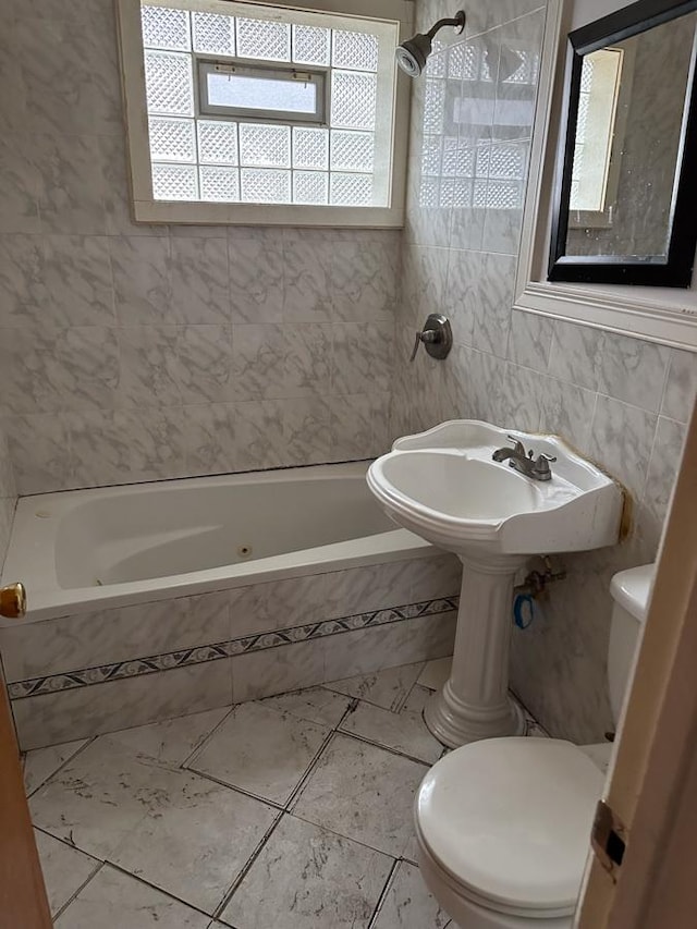 bathroom featuring tile patterned flooring, toilet, tile walls, and tiled shower / bath