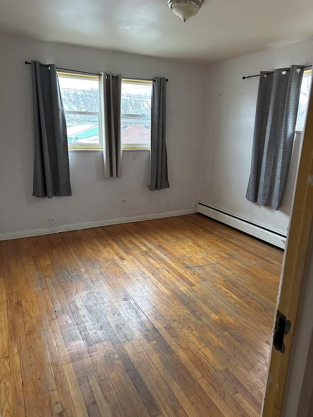 spare room with a baseboard heating unit and hardwood / wood-style floors