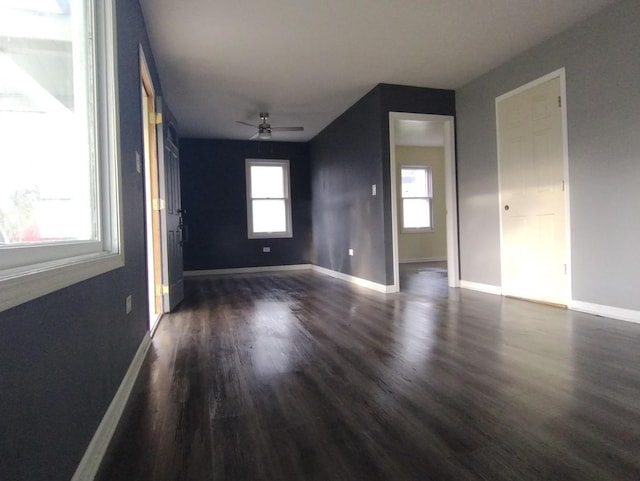 empty room featuring dark wood-type flooring, ceiling fan, and a healthy amount of sunlight