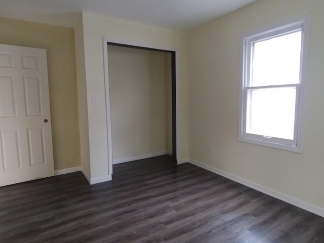 unfurnished bedroom featuring dark hardwood / wood-style floors, a closet, and multiple windows