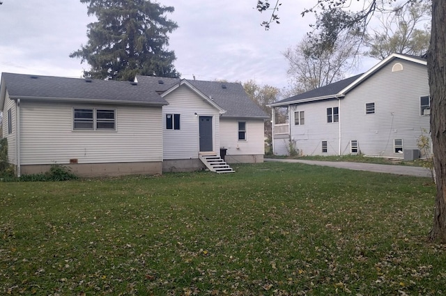 rear view of property featuring a lawn and cooling unit