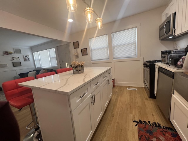 kitchen with pendant lighting, a kitchen bar, white cabinetry, and appliances with stainless steel finishes