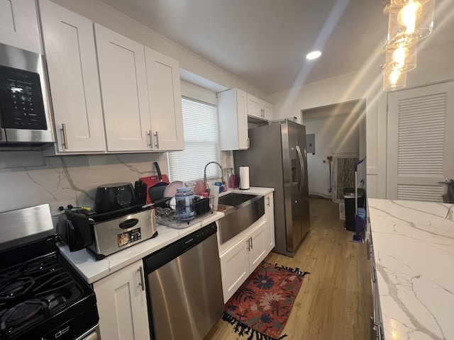 kitchen featuring tasteful backsplash, stainless steel appliances, sink, light hardwood / wood-style flooring, and white cabinets