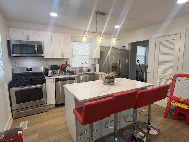 kitchen with pendant lighting, white cabinets, sink, appliances with stainless steel finishes, and tasteful backsplash