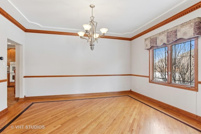 unfurnished room featuring a notable chandelier, ornamental molding, and wood-type flooring