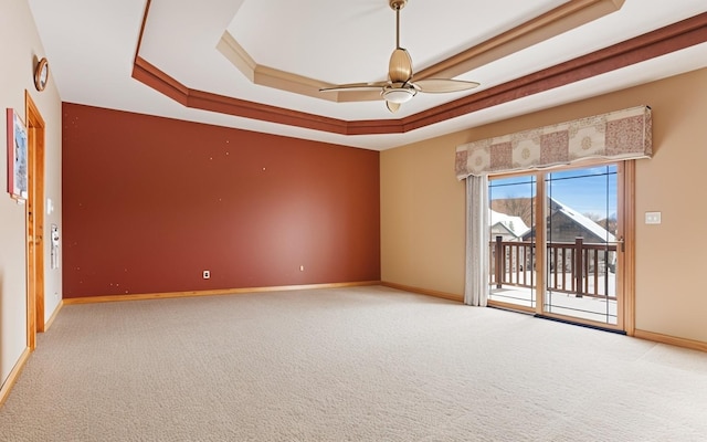 spare room featuring a raised ceiling, ceiling fan, and light colored carpet