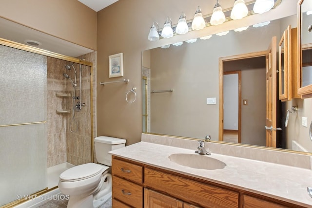 bathroom featuring toilet, tile patterned floors, a shower with shower door, and vanity