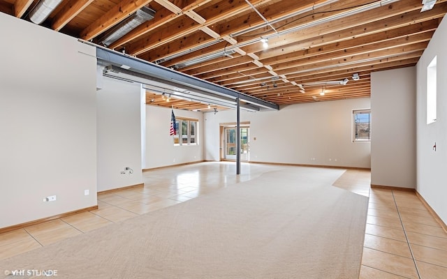 basement with track lighting and light tile patterned flooring