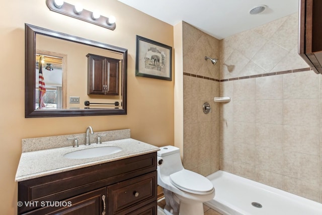 bathroom with tiled shower, vanity, and toilet