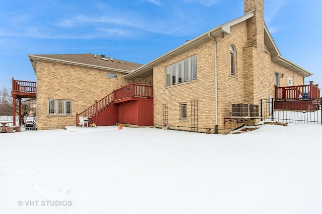 snow covered rear of property with a deck