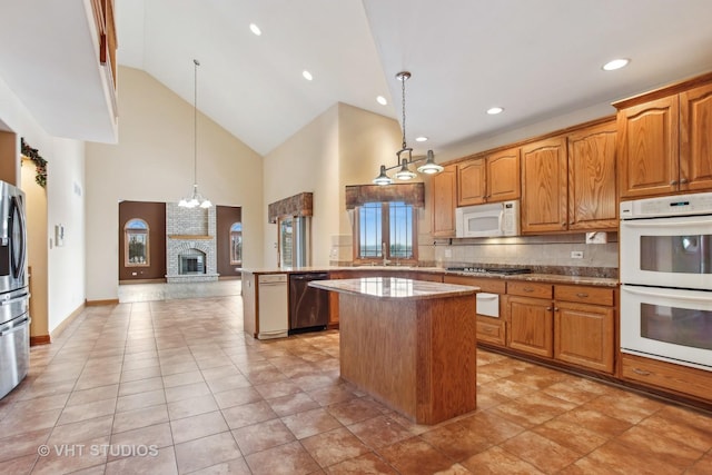 kitchen featuring kitchen peninsula, decorative light fixtures, tasteful backsplash, a kitchen island, and appliances with stainless steel finishes