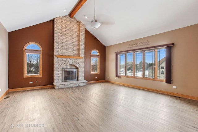 unfurnished living room with a fireplace, light wood-type flooring, ceiling fan, and beamed ceiling