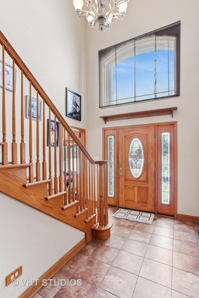 tiled entrance foyer featuring a towering ceiling and a chandelier