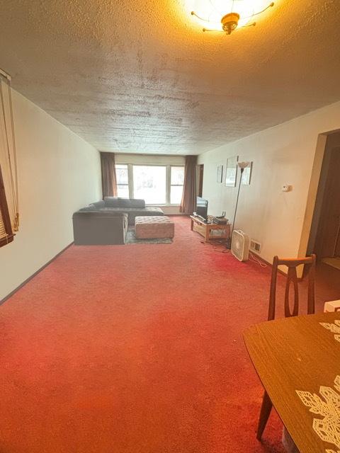 unfurnished living room featuring carpet flooring and a textured ceiling