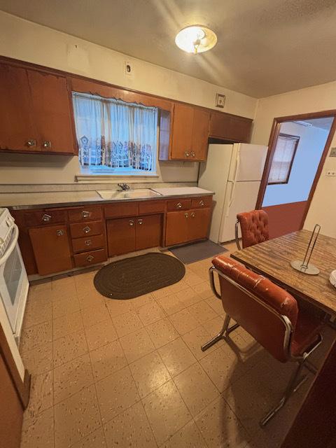 kitchen featuring range, white refrigerator, and sink