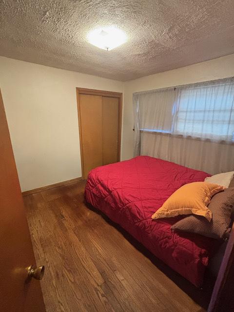 bedroom featuring hardwood / wood-style floors, a textured ceiling, and a closet