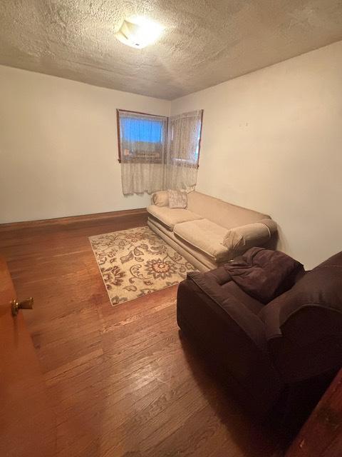 living room with wood-type flooring and a textured ceiling