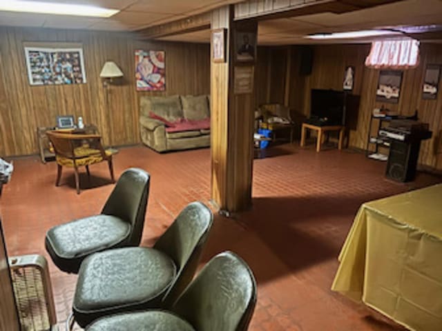 basement featuring a drop ceiling and wood walls