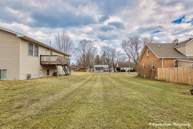 view of yard featuring fence, a deck, and stairs