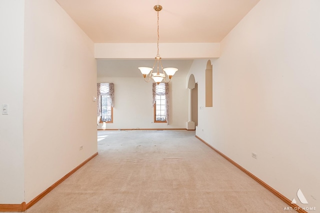 carpeted empty room with a chandelier