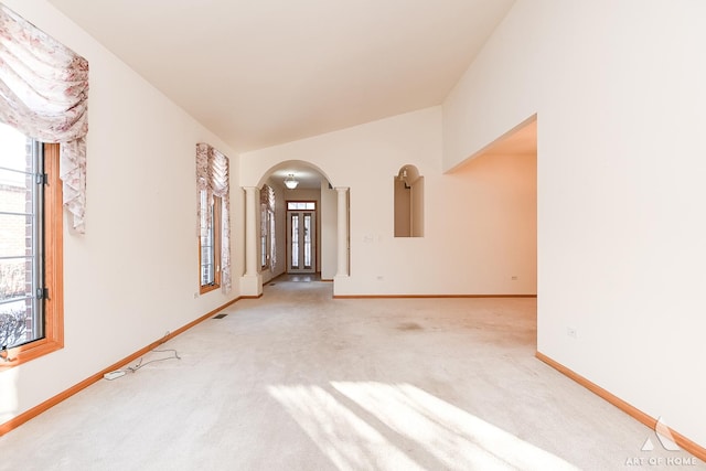 spare room with light carpet, vaulted ceiling, and a healthy amount of sunlight