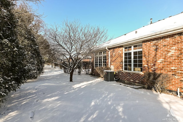 snow covered patio featuring central AC unit