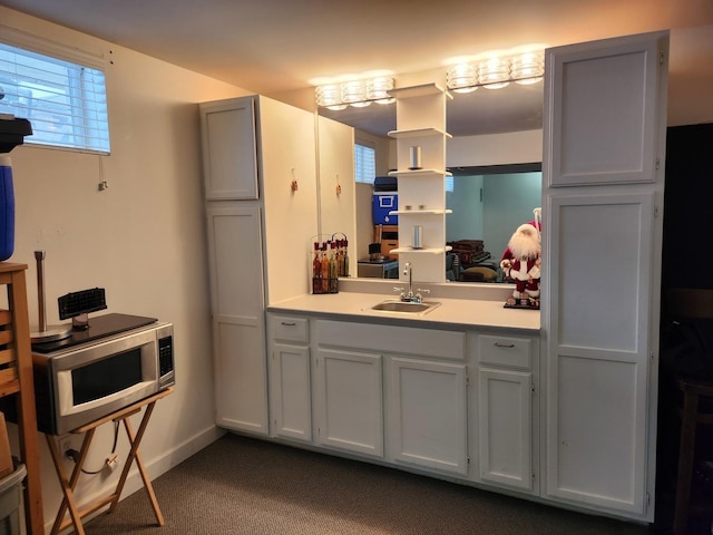 kitchen featuring sink, white cabinets, and carpet flooring