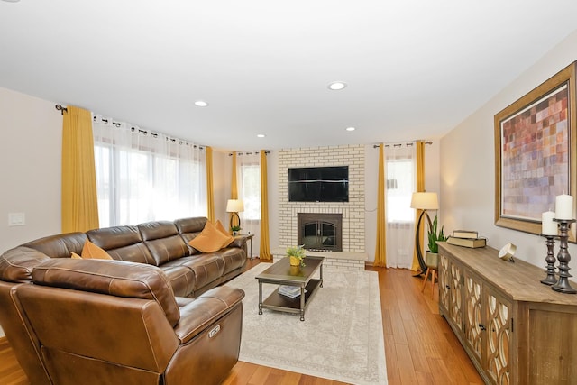 living room with a brick fireplace and light hardwood / wood-style flooring