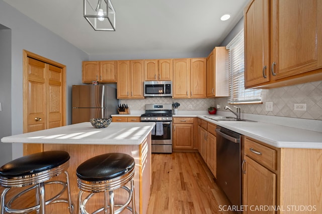 kitchen with sink, a center island, light hardwood / wood-style flooring, appliances with stainless steel finishes, and a kitchen breakfast bar