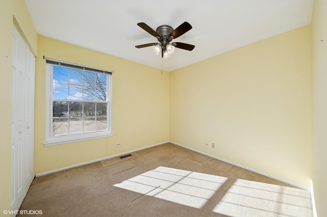 empty room featuring baseboards, visible vents, ceiling fan, and light colored carpet