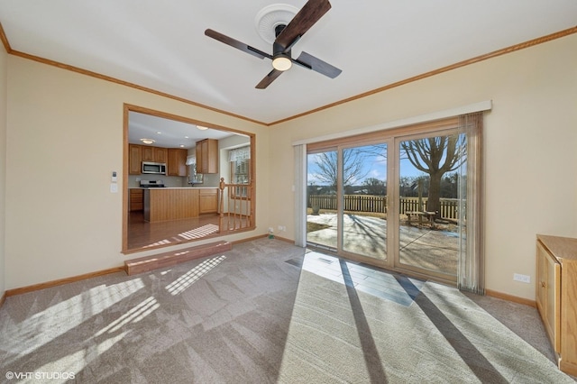 interior space with ornamental molding, light carpet, baseboards, and a ceiling fan