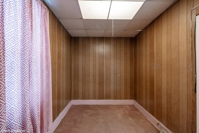 spare room with carpet floors, a paneled ceiling, and wooden walls