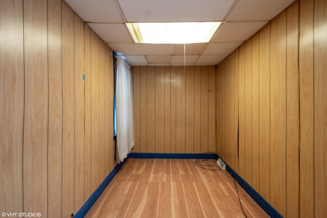 spare room featuring light wood-type flooring, a paneled ceiling, and wooden walls